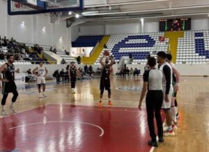 Basketbol sahasında oyuncular ve hakemler, maç heyecanı.